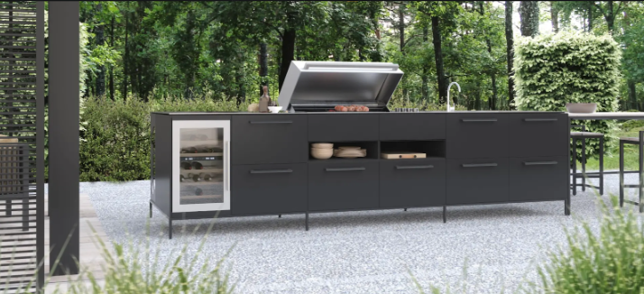 Modernios lauko virtuvės dizaino pavyzdys – INNI dizainas – elegantiška ir funkcionali lietuviško gamintojo INNI lauko virtuvė su integruota kepsnine, plautuve ir vyno šaldytuvu. Stilingas ir praktiškas sprendimas lauko maisto ruošai, harmoningai įsiliejantis į gamtos apsuptį.